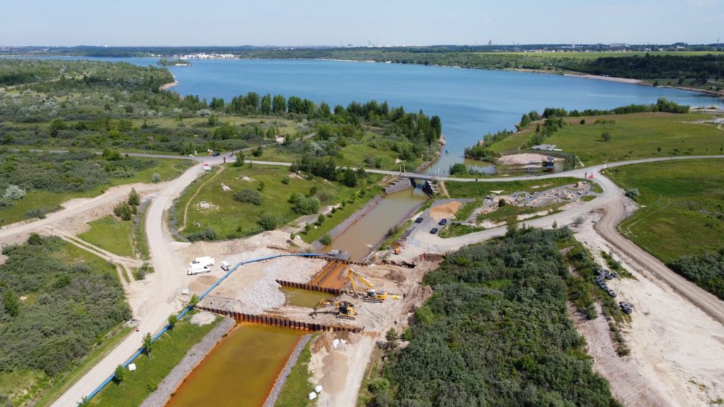 Im Vordergrund das untere Querbauwerk, bestehend aus 3 Spundwänden. Dahinter der Markleeberger See.